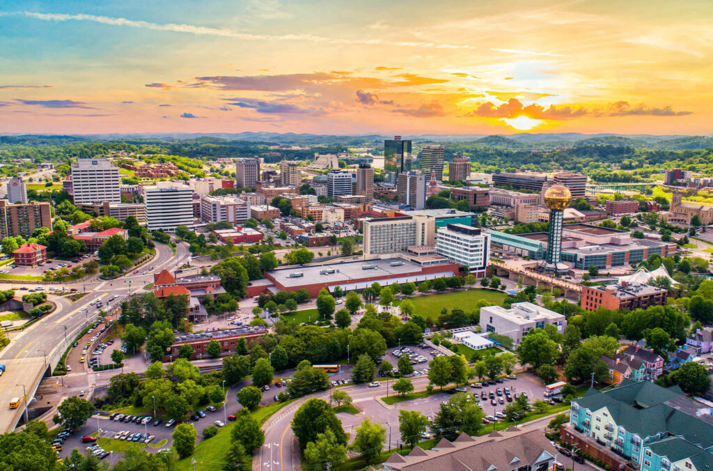 Aerial view of the city of Knoxville with mountains in the background during sunset