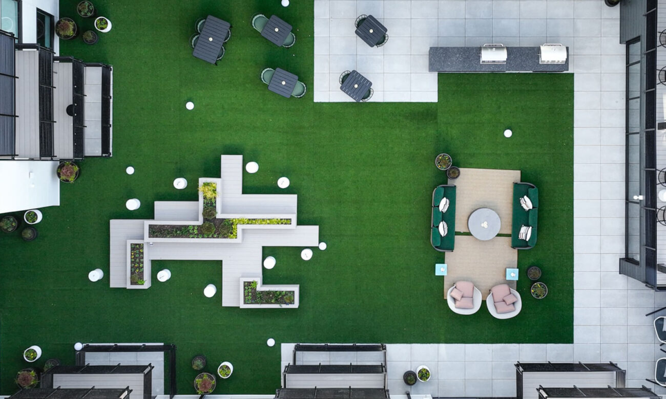 Aerial view of outdoor courtyard with artificial grass flooring, lots of seating options, and two grills.